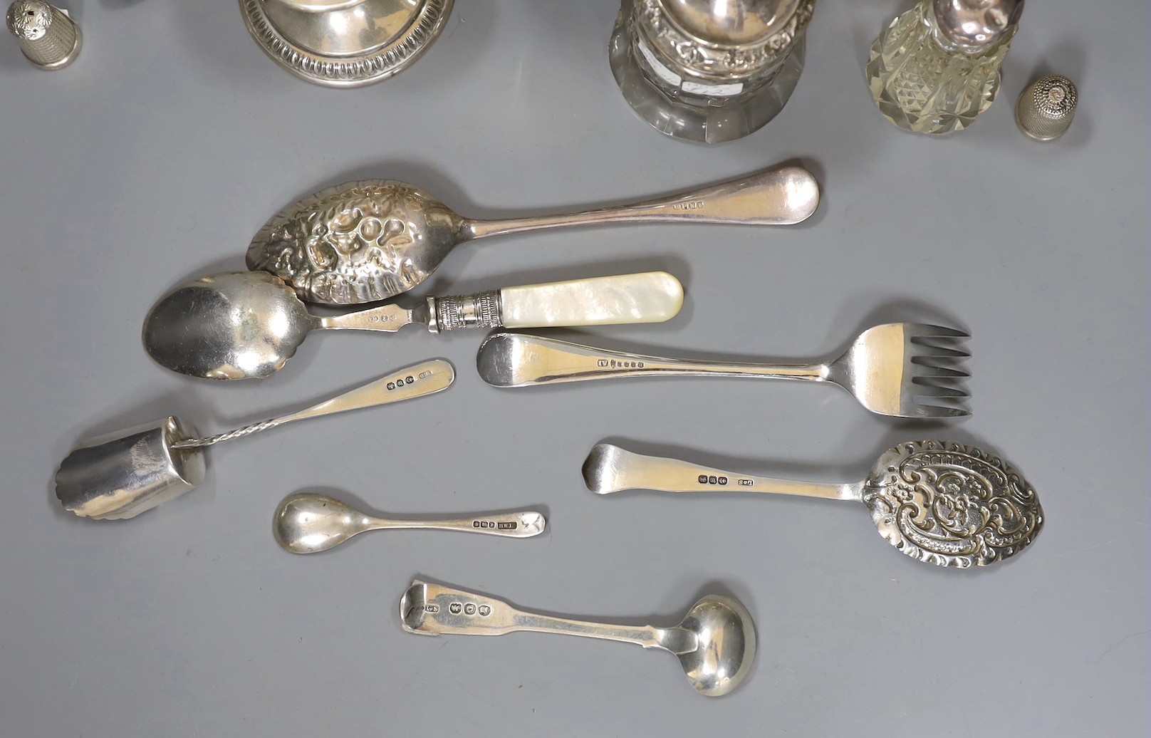 Small silver items including 800 standard dwarf candlestick, a George V silver mounted pin cushion, a silver mounted glass atomiser and two toilet jars, a sterling lighter, two silver thimbles, four items of silver flatw